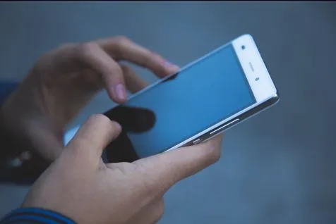 Hands holding mobile phone and beginning to type.
